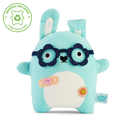 A light blue plush bunny toy with a white belly, dark blue glasses, and small embroidered details, shown on a white background with a green 'Noddoll Pre-Loved' badge in the top-left corner.